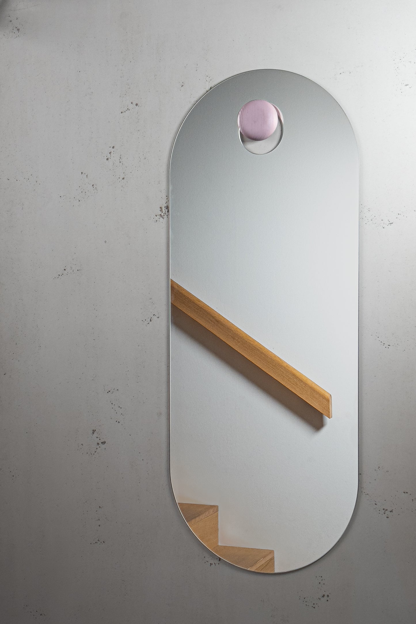 Unser elegante Körperspiegel hängt an einem rosapink gebeizten Holzknopf. Im Spiegelbild spiegelt sich eine moderne Einrichtung aus Eiche