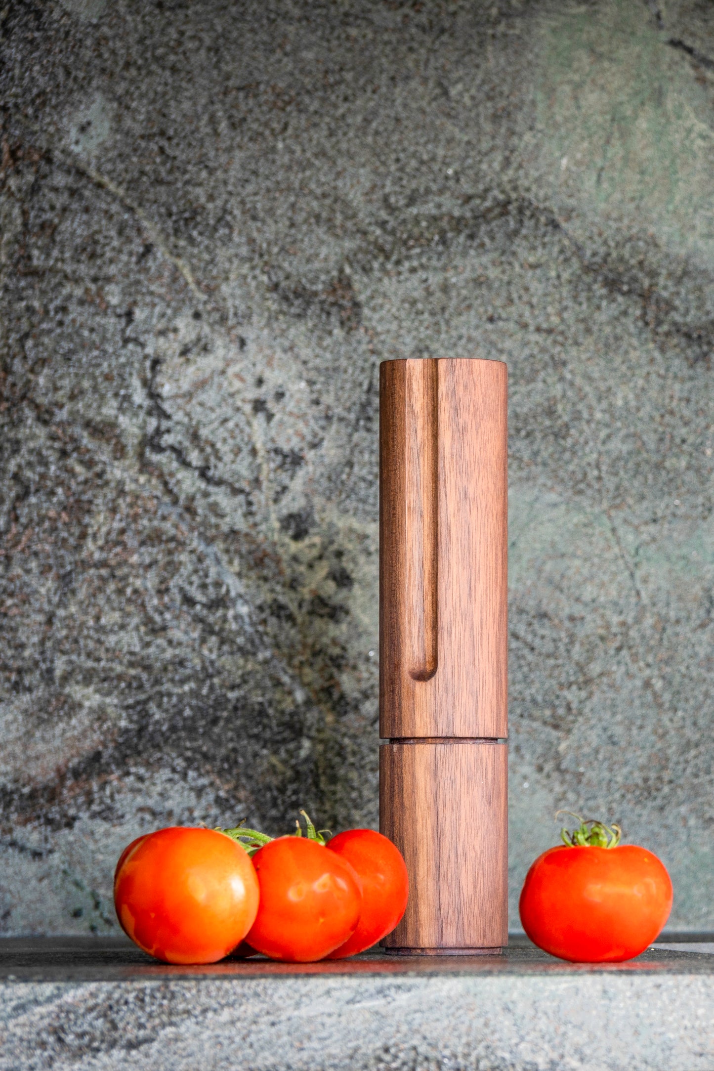 Unsere exklusive Pfeffermühle aus Wallnussholz, umgeben von stilvollem Naturstein und saftigen Tomaten. minimalistisches und modernes Design. Jedes Pfeffermühle ist ein Unikat hoher Drechselkunst!