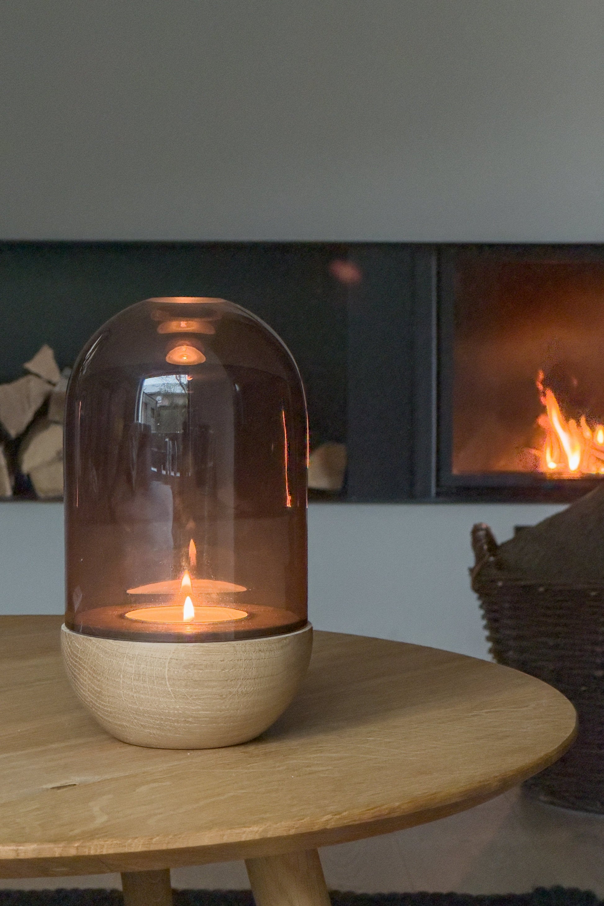 GLOW Windlicht aus Rauchglas und Eiche im Wohnzimmer mit Kaminfeuer